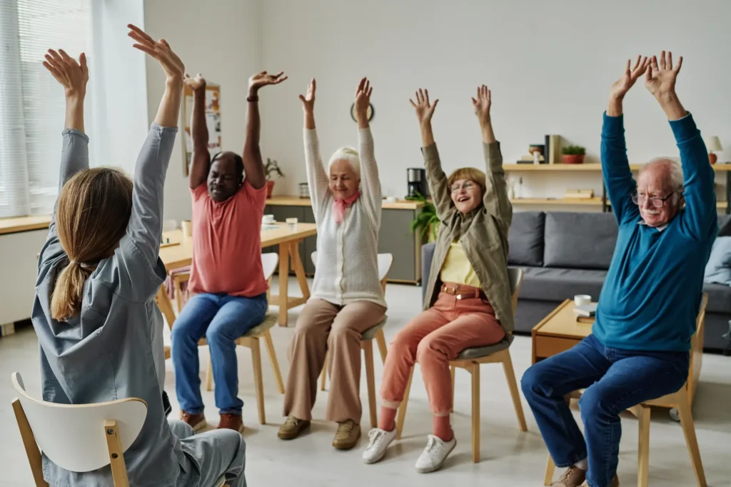 An elderly class on doing chair yoga, one of the best mobility exercises for senoirs at Clarendale Clayton in MO.