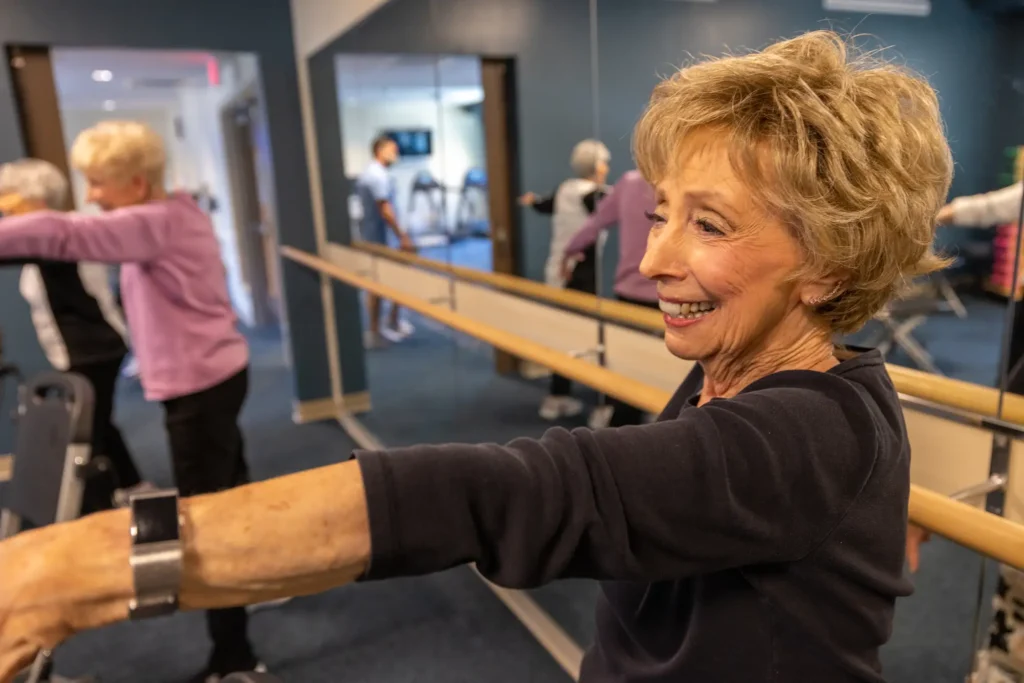 Senior woman in group fitness class an smiling about the senior living amenities at Clarendale Clayton in MO.