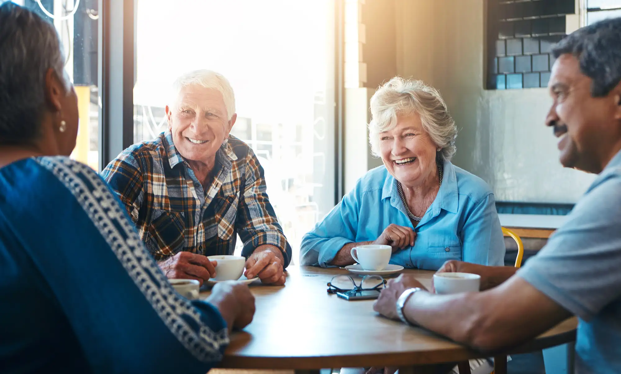 Two senior couples sitting at a table and drinking coffee